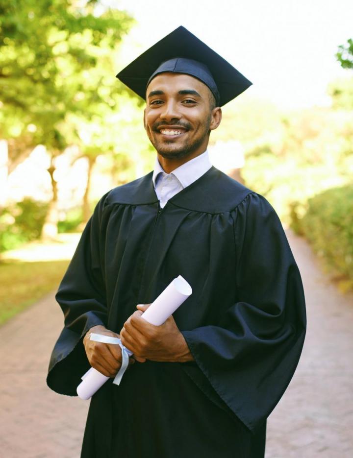 Photo of a person graduating in a cap and gown while holding a diploma