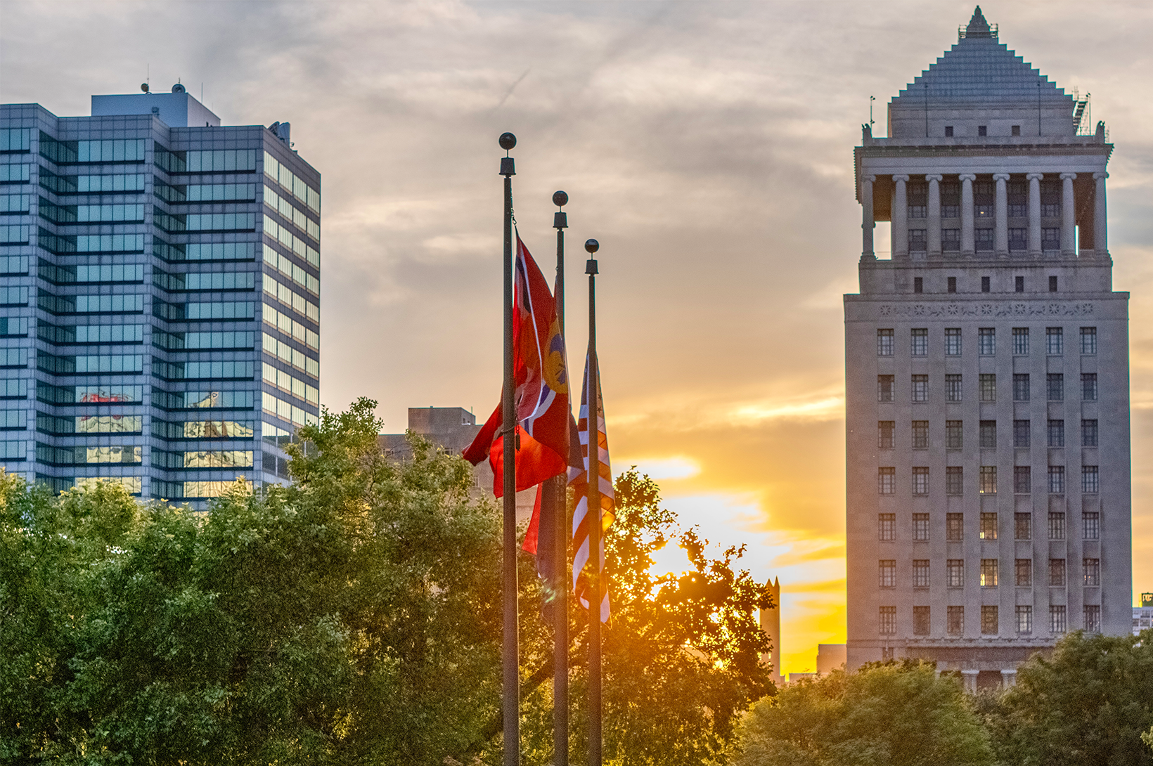 Aerial photo of Downtown St. Louis at sunset, looking past city flags to the skyline.