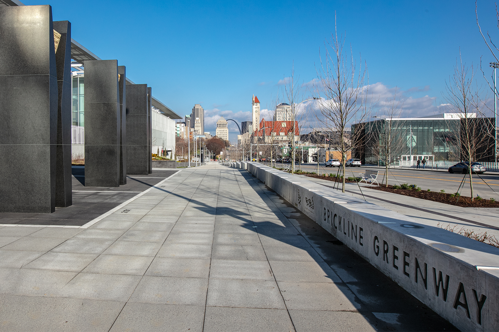 An image of Brickline Greenway signage in the foreground, with the St. Louis skyline in the background.