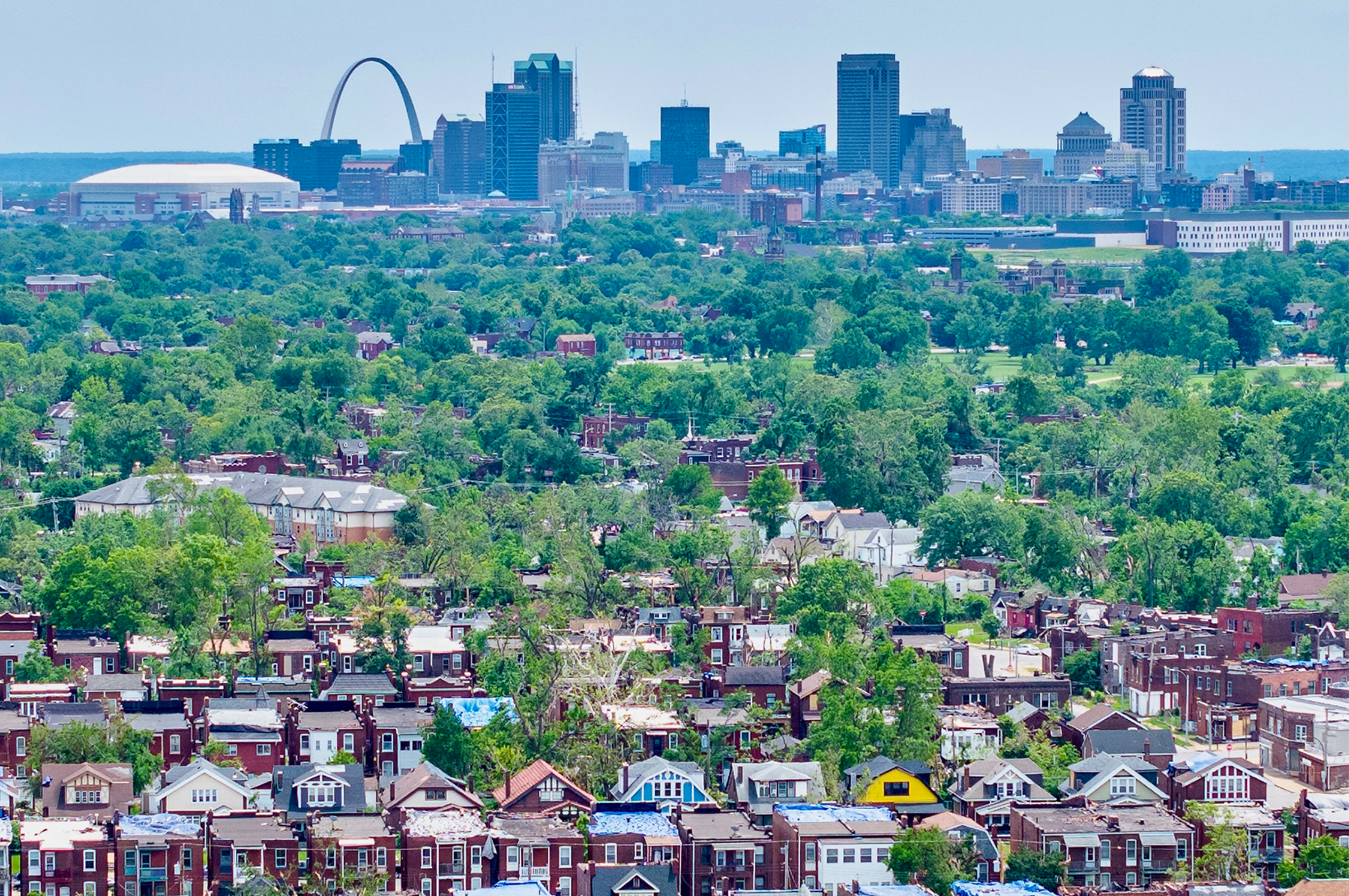 A view of the St. Louis skyline after the May 16, 2025, tornado. Blue-tarped roofs are seen in the foreground.