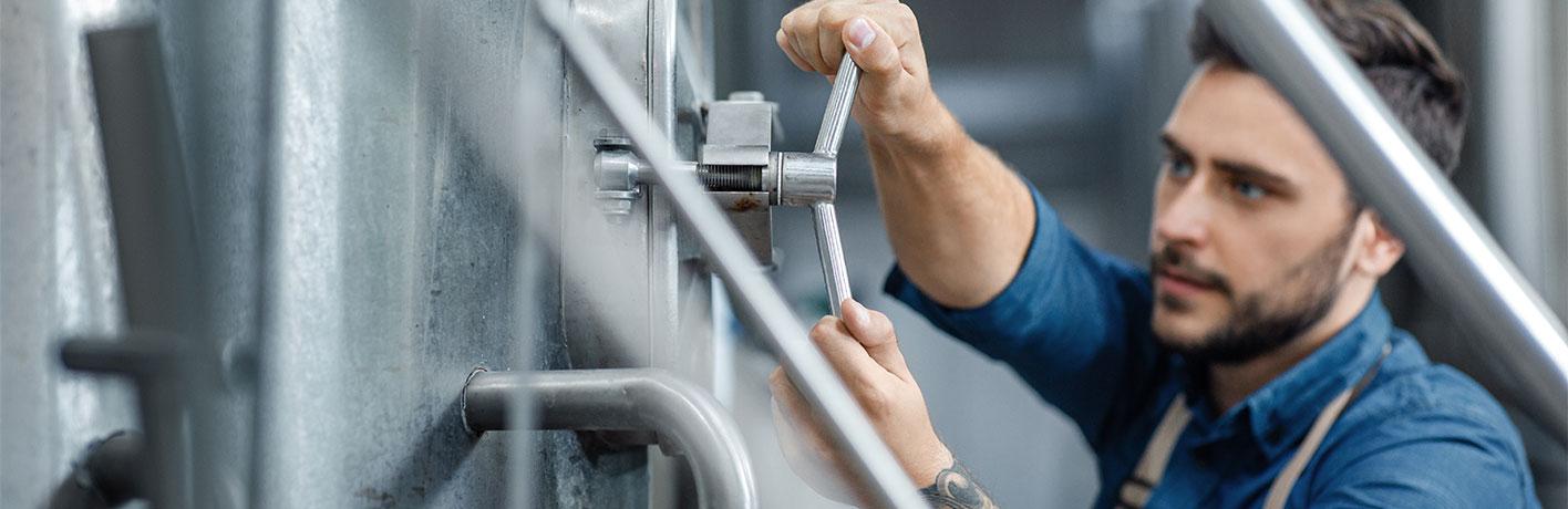 A man working in a brewery is turning a handle