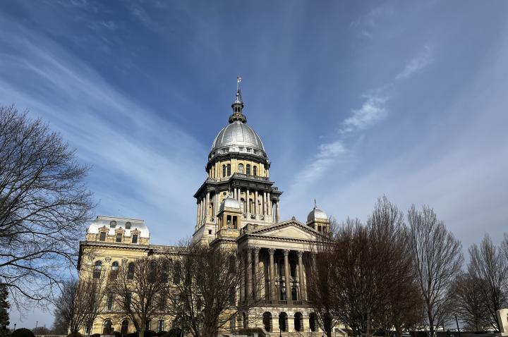 Exterior photo of the Illinois Capitol building, set against a wide blue sky.