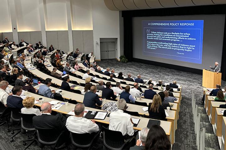 People sit in an auditorium at Washington University, listing to an expert at the 2023 St. Louis Crime Summit.