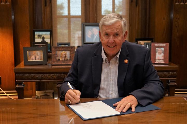 Governor Parson signs bills at his desk in Jefferson City.