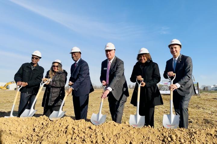 Six business and civic leaders stand with shovels and hard hats at the new PFG facility in North St. Louis County.