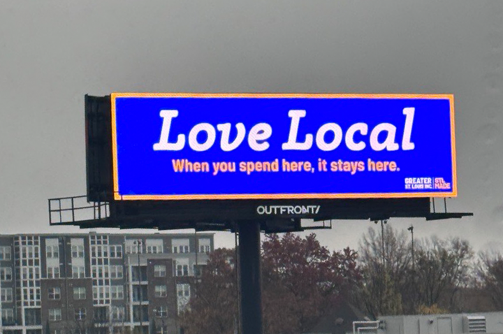 A bright blue Love Local billboard reminds St. Louis shoppers to buy local.
