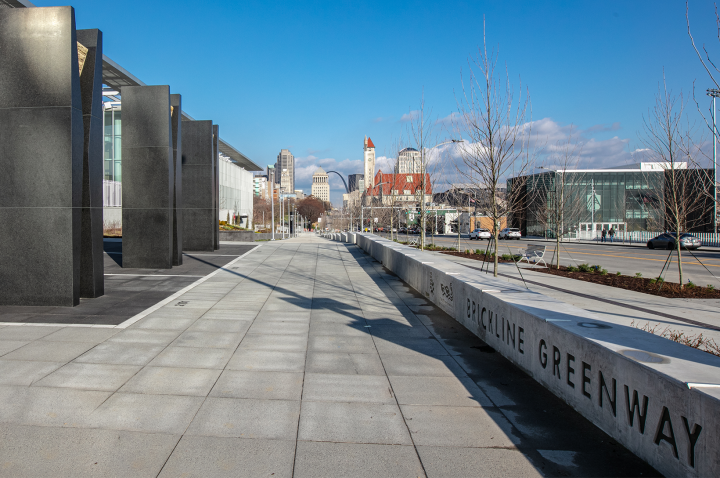 An image of Brickline Greenway signage in the foreground, with the St. Louis skyline in the background.