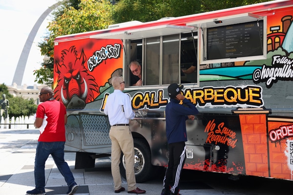 Front façade of a red-brick building housing the National Blues Museum, with a vintage marquee reading Blues Museum, tall green-framed windows, decorative stone trim, and several cars parked along the street.