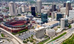 Aerial view of downtown with a red-seated baseball stadium next to skyscrapers, parking lots and highways.