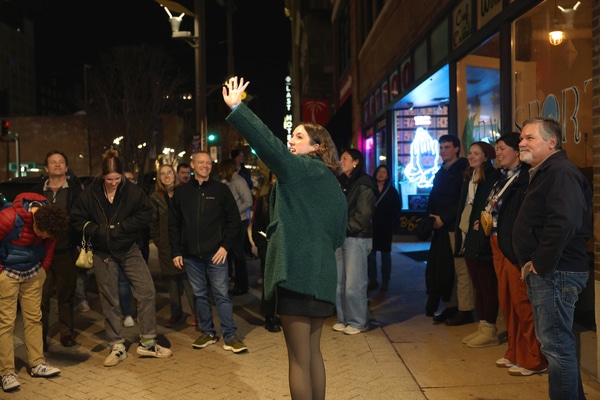 Front façade of a red-brick building housing the National Blues Museum, with a vintage marquee reading Blues Museum, tall green-framed windows, decorative stone trim, and several cars parked along the street.