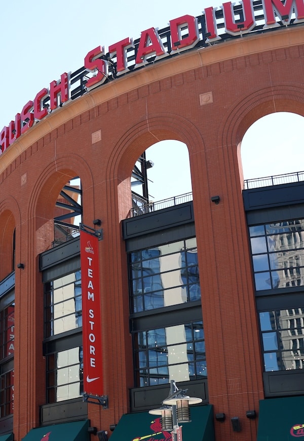 Busch Stadium's red-brick arched facade with large STADIUM lettering and a vertical red TEAM STORE banner