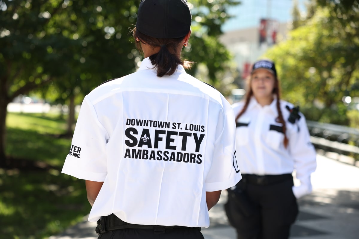 Three patrons seated on wooden barstools at a long wooden bar in a cozy pub with exposed beams, multiple beer taps, a menu board on a pillar and a decorative crest above the mirror-backed bar