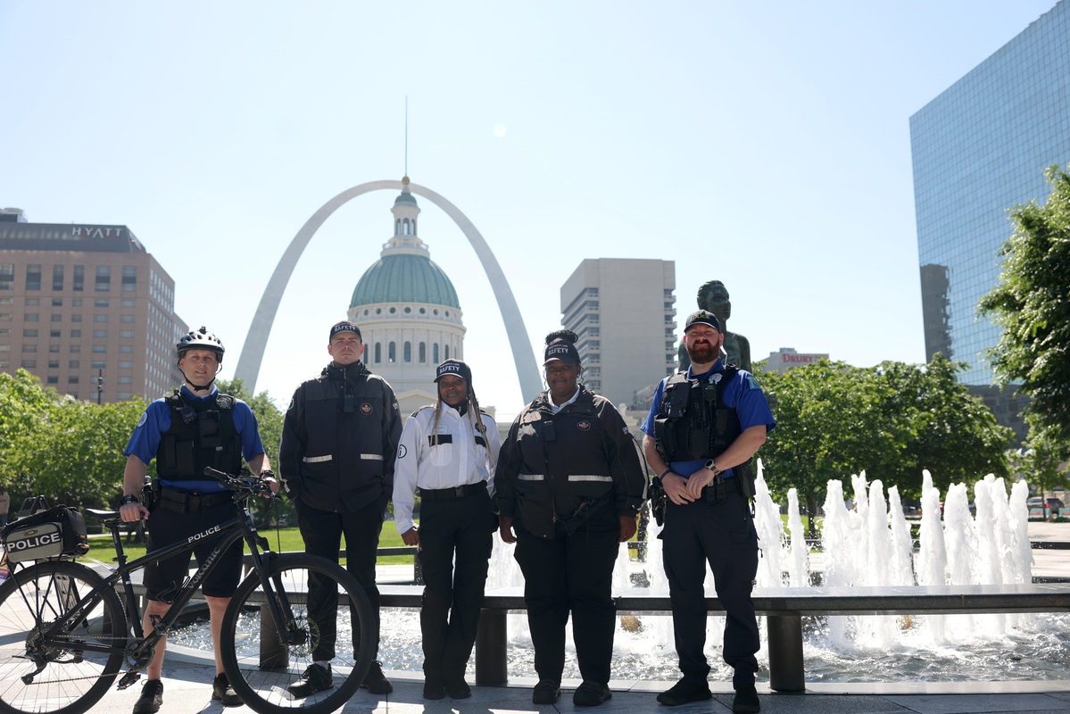 Rustic bar interior with patrons seated at a blue-tiled counter, hanging star-shaped metal lanterns under exposed wooden beams, a large TV broadcasting sports above the bar, and colorful decorative wall plates on a corrugated wall.