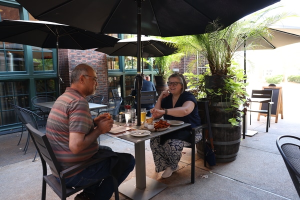 Stainless-steel Gateway Arch towering over a broad green park with a circular fountain and walkways, framing the downtown St. Louis skyline under a bright blue sky.