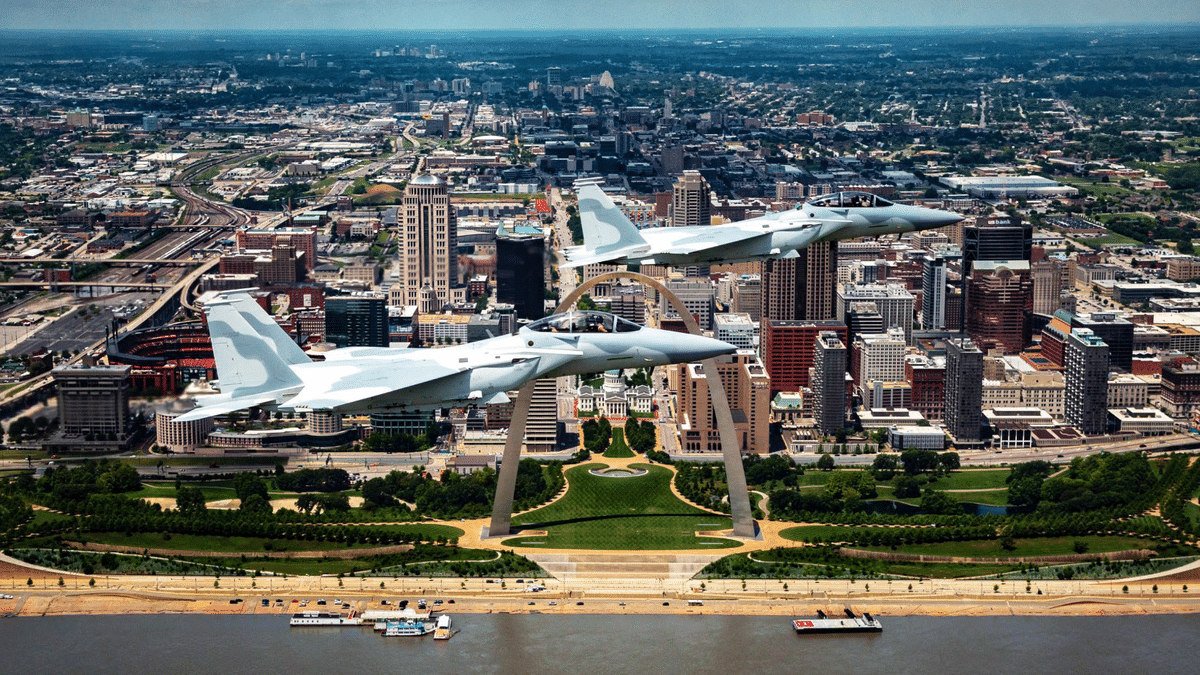 jets aerial-1200×675-c2b5ff2 Two gray fighter jets flying in formation over downtown St. Louis with the Gateway Arch and riverside park below.