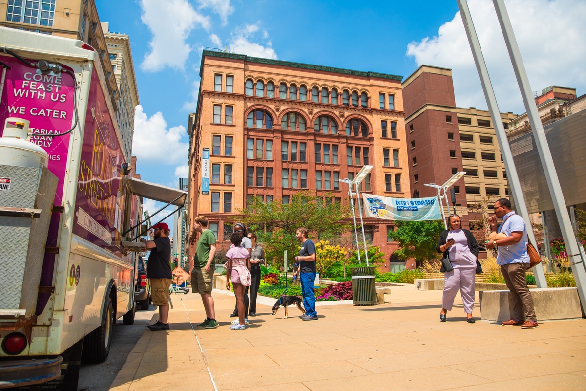 Front façade of a red-brick building housing the National Blues Museum, with a vintage marquee reading Blues Museum, tall green-framed windows, decorative stone trim, and several cars parked along the street.