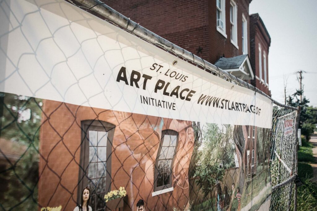 St. Louis Art Place Initiative banner on a chain-link fence in front of a brick building