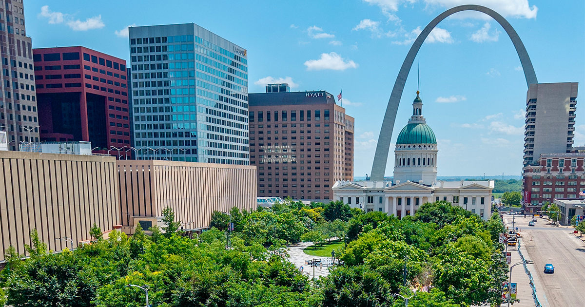 St. Louis skyline with the Gateway Arch behind the domed Old Courthouse, framed by downtown buildings and green trees