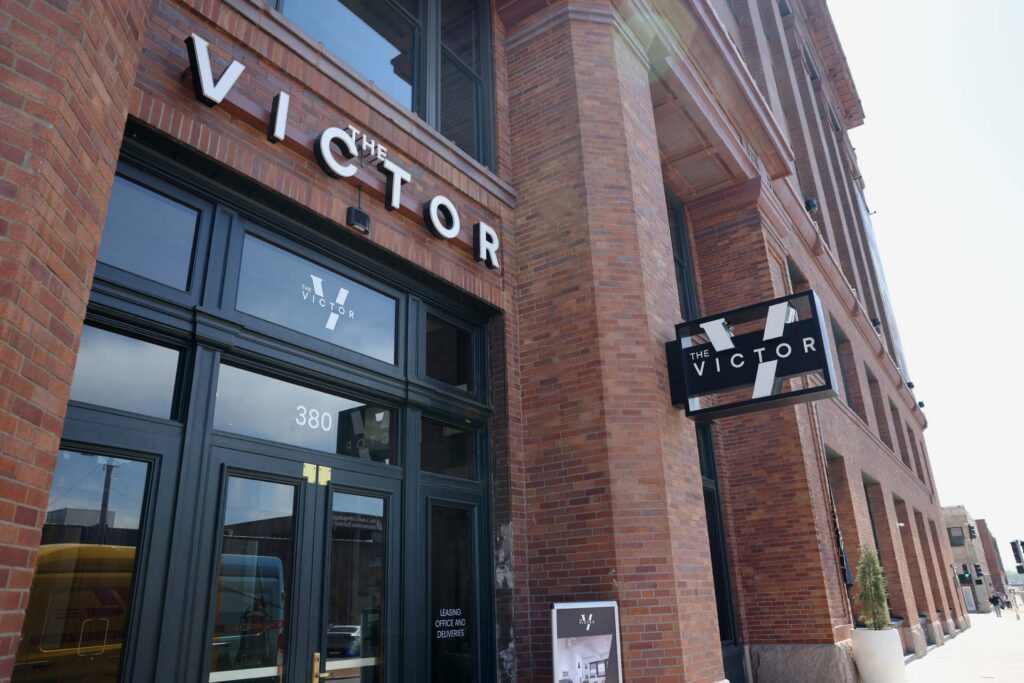 Corner entrance of The Victor, a red brick building with signage and a leasing office at address 380