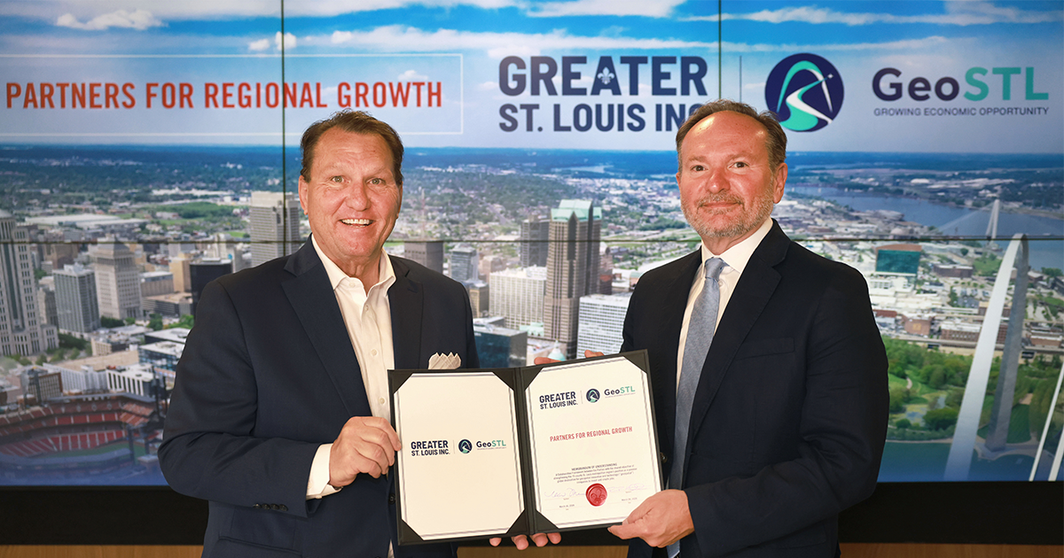 Two men in suits hold a signed Greater St. Louis Inc. and GeoSTL "Partners for Regional Growth" agreement