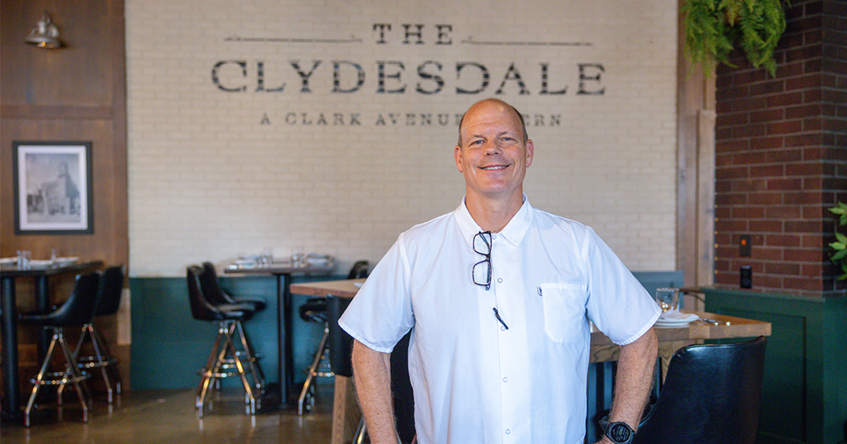 Smiling man in a white shirt standing inside The Clydesdale, A Clark Avenue Tavern