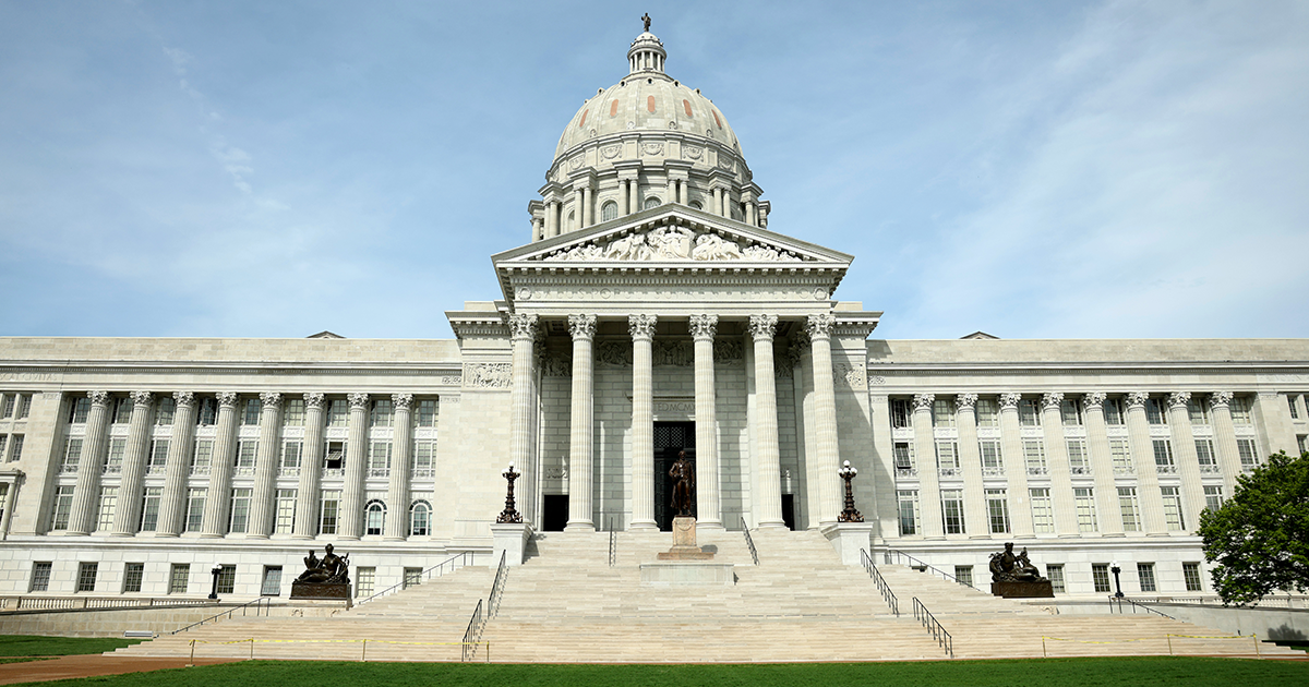 Missouri State Capitol building with its central dome, columned portico, and front steps under a blue sky